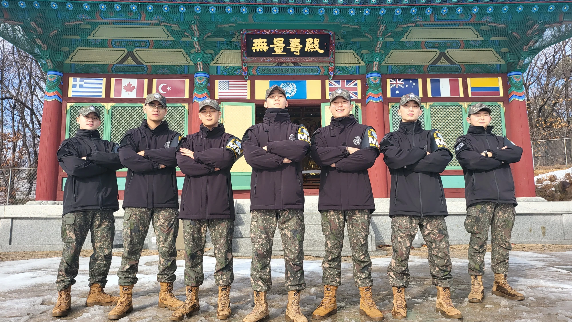 Joshua Lee with his Joint Security Area unit, standing beneath the flags of the United Nations Command member nations.